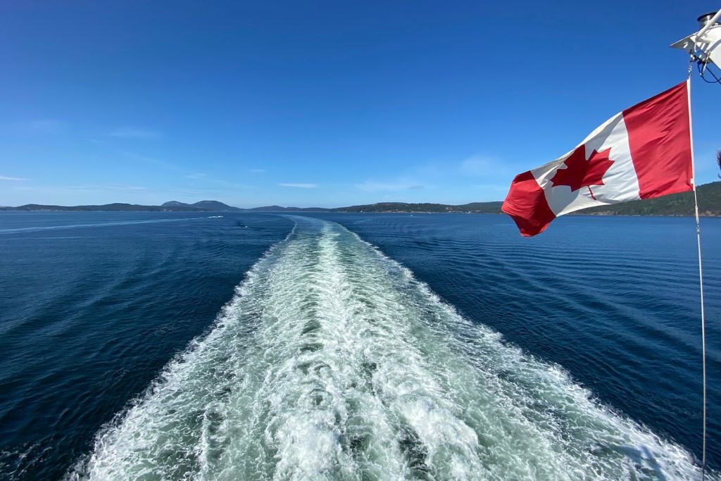 A Canadian flag and the trail behind a ferry to Vancouver Island on Map