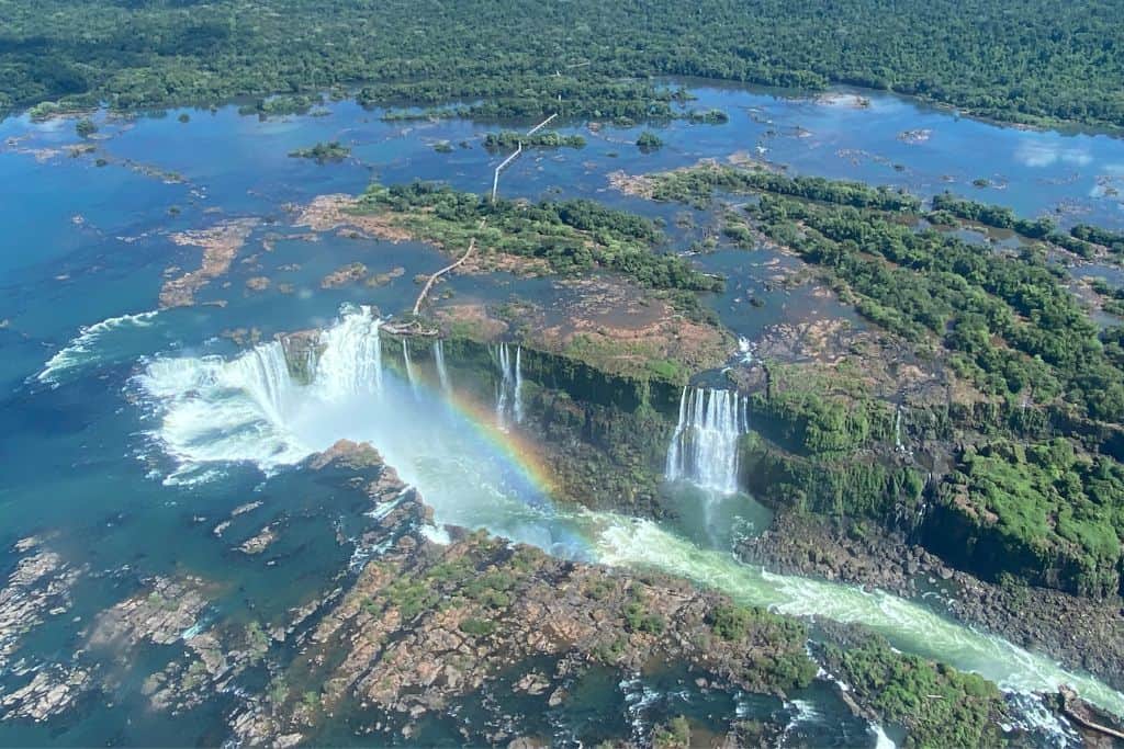 Views of Iguazu Falls and the expansive Iguazu River from the Helicopter, with a rainbow at the centre of the cascading waterfall