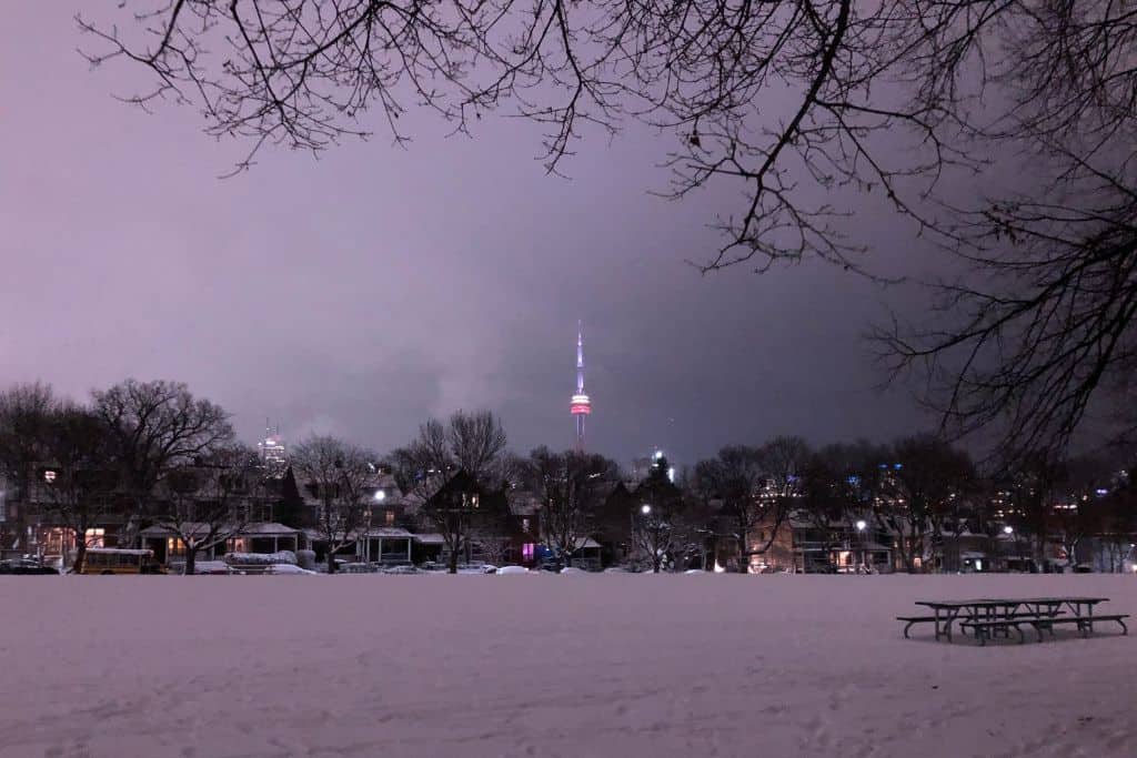 A view of the CN Tower from snow-covered Trinity Bellwoods Park during winter in Toronto.