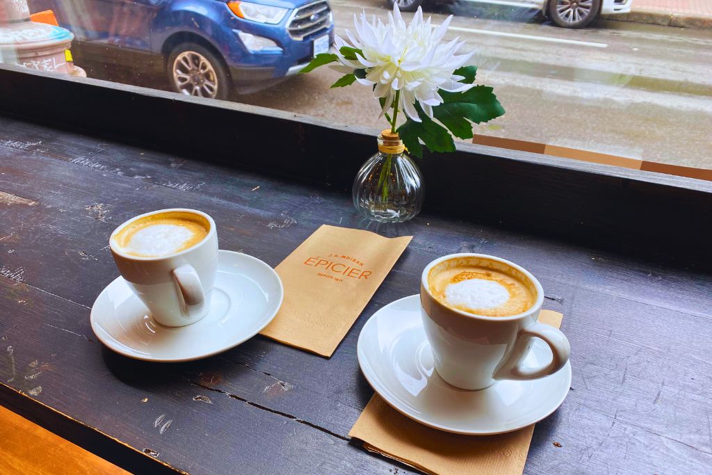 Two cups of coffee in a Quebec City cafe, where tipping culture and added taxes make dining out expensive, which can be a reason not to move to Canada.