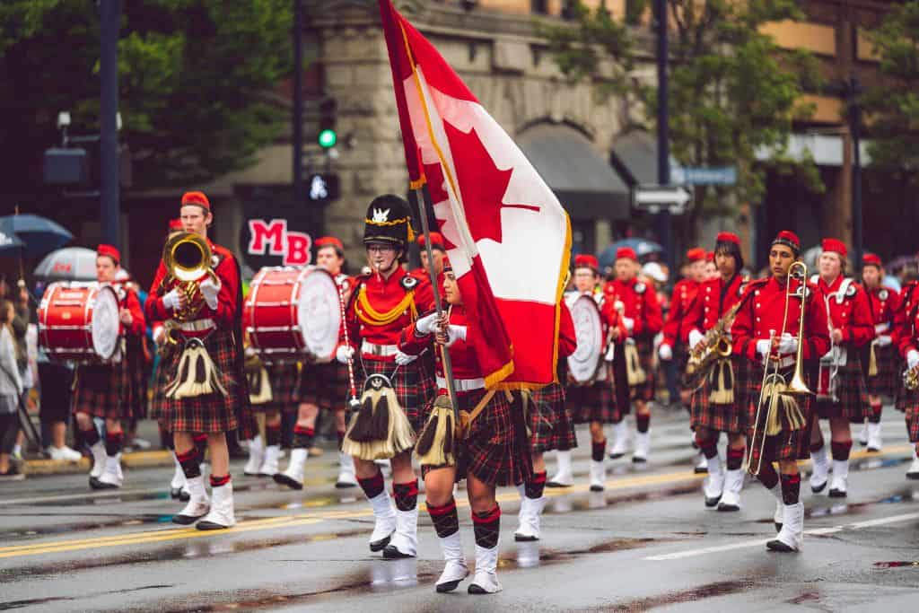 Do you regret moving to Canada? A marching band dressed in red holding up a Canadian flag and marching down the street