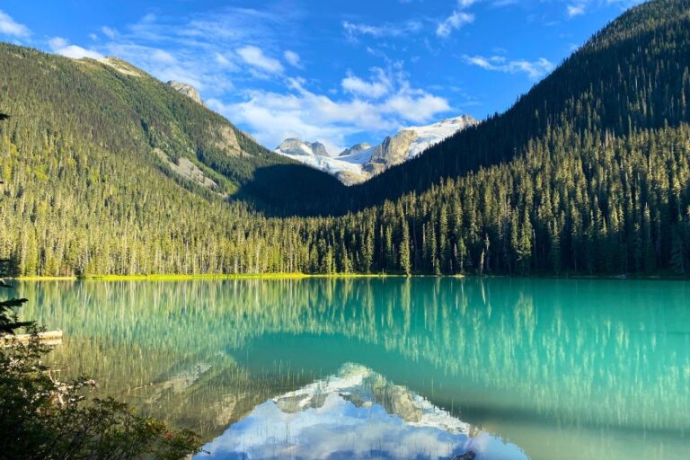 The reflection of the mountains in the bright blue water of a lake on the Joffre Lakes Hike in Canada.