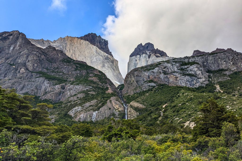 Two two-toned granite mountain peaks surrounded by green shrubs at the base.