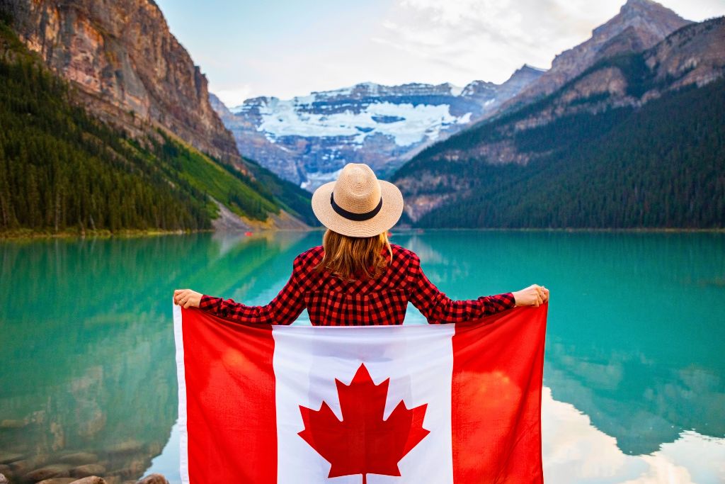 Do I need an immigration lawyer? A woman holding up the Canadian flag at Lake Louise in Alberta, Canada.