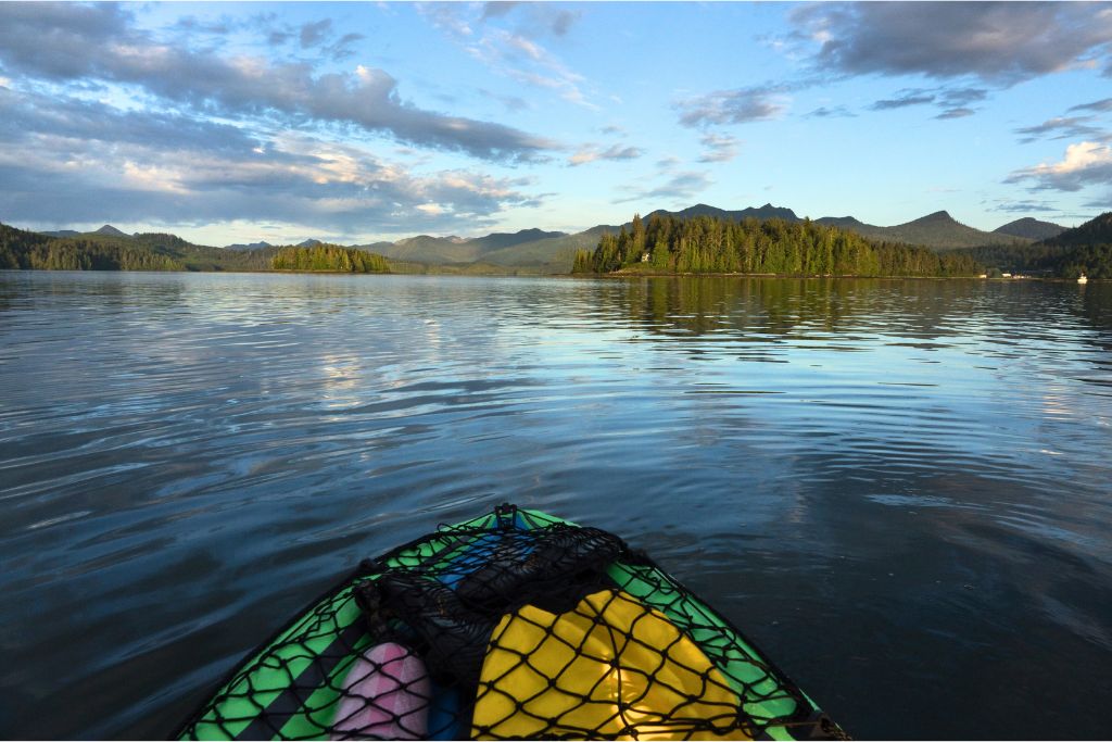 The tip of a green kayak which is paddling through Haidi Gwaii in British Columbia.