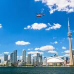 A helicopter flying over Lake Ontario with the Toronto skyline in the background on one of the Toronto helicopter tours.