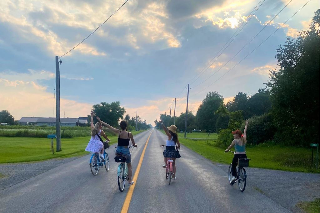 Four women cycling along a tree-lined country road on one of the best Niagara wine tours.