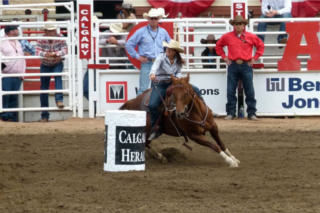 A cowgirl barrel racing at the Calgary Stampede, which is one of Canada's biggest festivals, and makes the list of pros and cons of living in Canada.