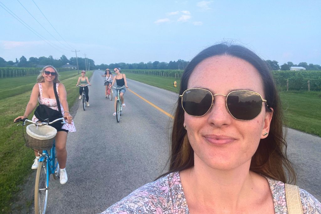 A group of women cycling down a country road in Niagara-on-the-Lake, on one of the Niagara bike wine tours.