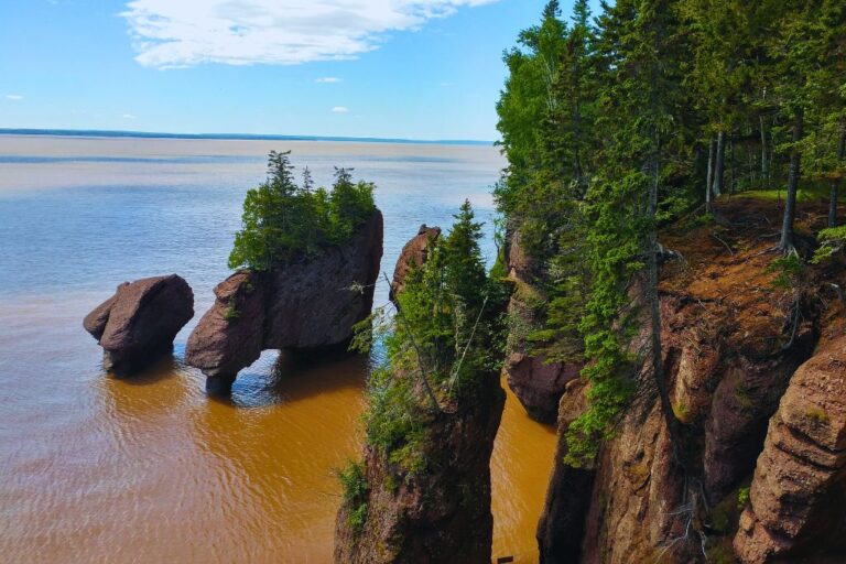Rock formations surrounded by brown water in Hopewell Rocks Cliffs Coast Park along the Bay of Fundy, home of the highest tides in the world.