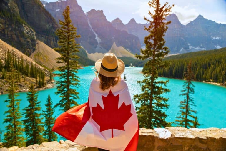 A woman at Moraine Lake posing with the Canada flag.
